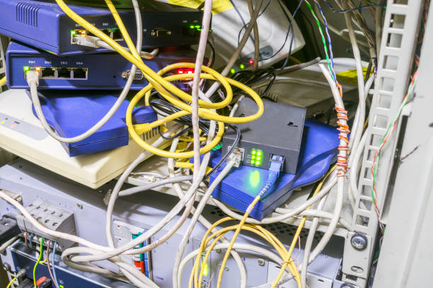 サーバー ネットワーク インターネット機器収納用キャビネット。カオスは、モデム、スイッチ、およびインターネット橋間のワイヤのインター レース。多くのネットワーク デバイスとケー - messy network server cable computer ストックフォトと画像