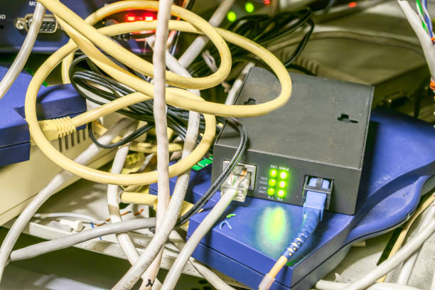 istock Chaotic interlacing of wires between the modem and the Internet bridge. Box with many network devices and cables. Server cabinet with network Internet equipment 1014595972