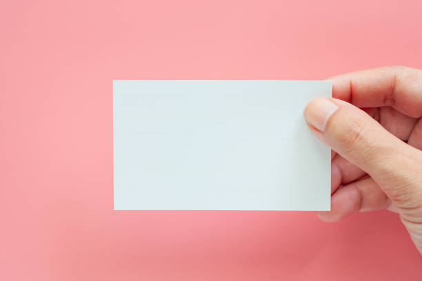istock Hand holding blank business cards on pink background 1014608864