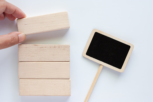 Hand picking the wooden toy with blackboard label stick on white background