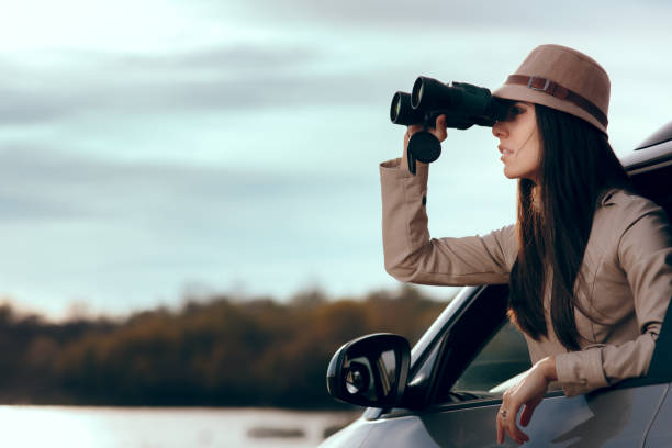 istock Female Detective Spying with Binocular from a Car 1014615994
