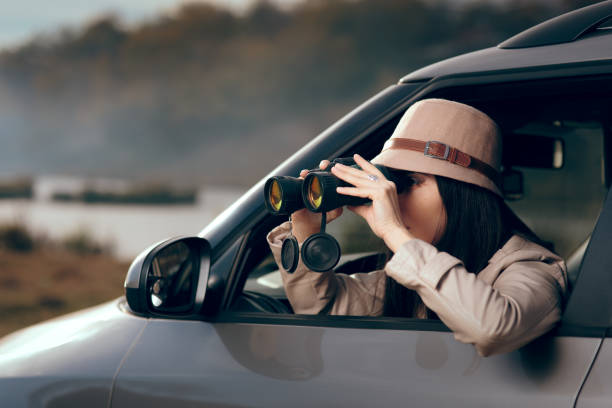 istock Female Detective Spying with Binocular from a Car 1014615996