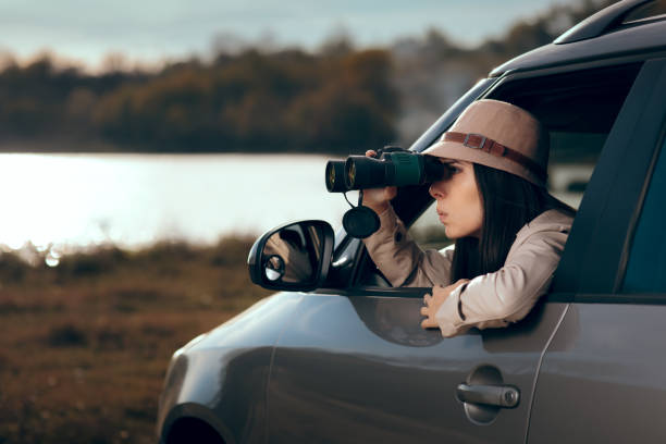 istock Female Detective Spying with Binocular from a Car 1014616254