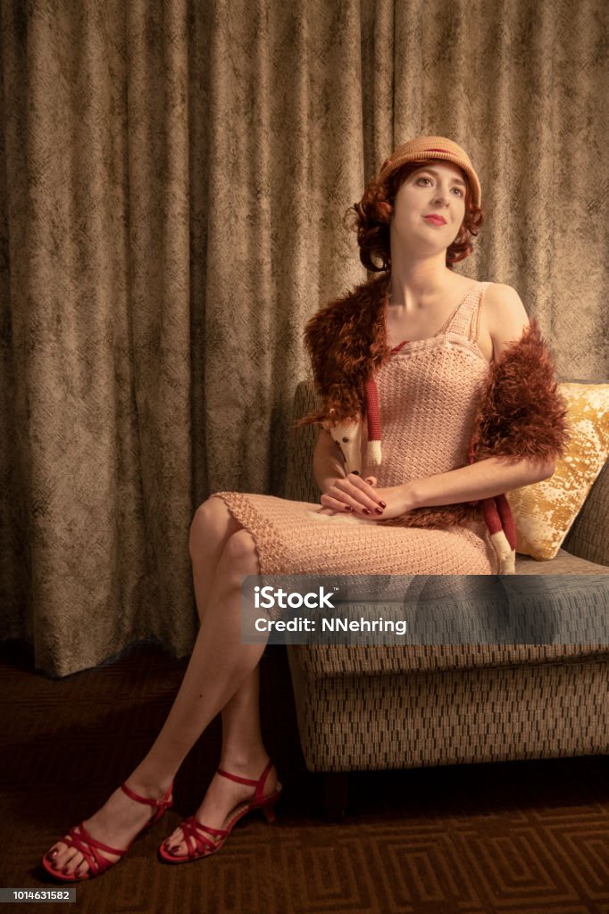 1920s flapper Young woman in 1920s flapper dress with fox fur and cloche sitting in a chair. 1920-1929 Stock Photo