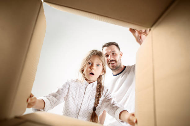 istock dad with daughter unpacking and opening carton box and looking inside 1014645412