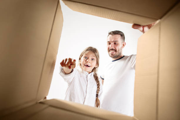istock dad with daughter unpacking and opening carton box and looking inside 1014645652