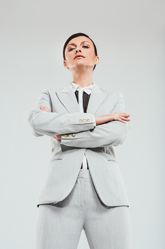 Studio portrait of an attractive and confident businesswoman folding her arms against a gray background