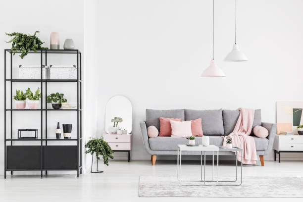 istock Lamps above table in white spacious living room interior with grey sofa with pink blanket. Real photo 1014655732