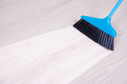 before and aftet cleaning concept - blue broom sweeping parquet floor