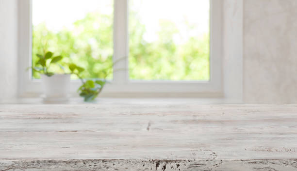 istock Bleached vintage wooden tabletop with blurred window for product display 1014658366