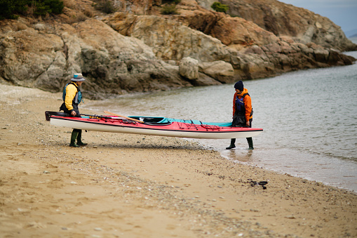 A man and a woman on a beach preparing to go sea kayaking