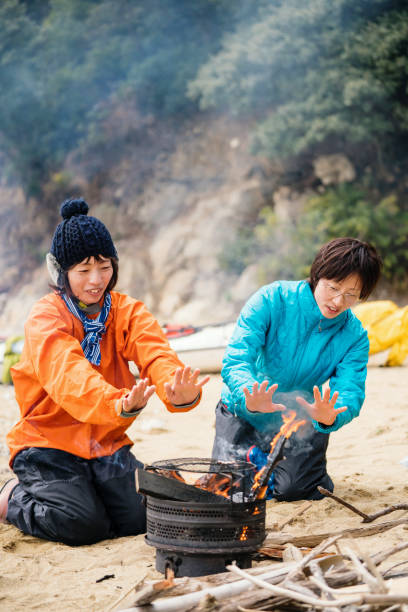 istock Two women warming up by a fire after sea kayaking 1014664368