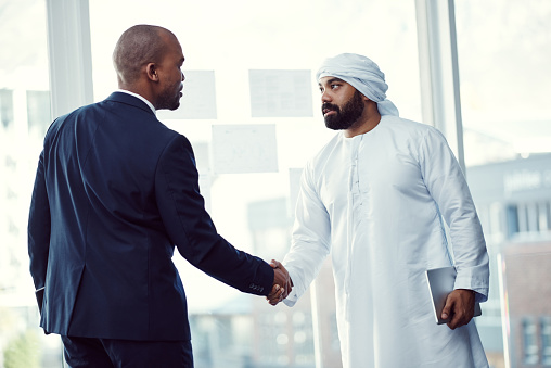 Shot of two businessmen shaking hands in a modern office