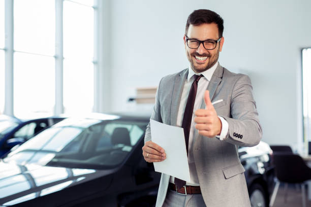 Salesperson at car dealership selling vehicles Salesperson at car dealership selling vehicles salesman stock pictures, royalty-free photos & images