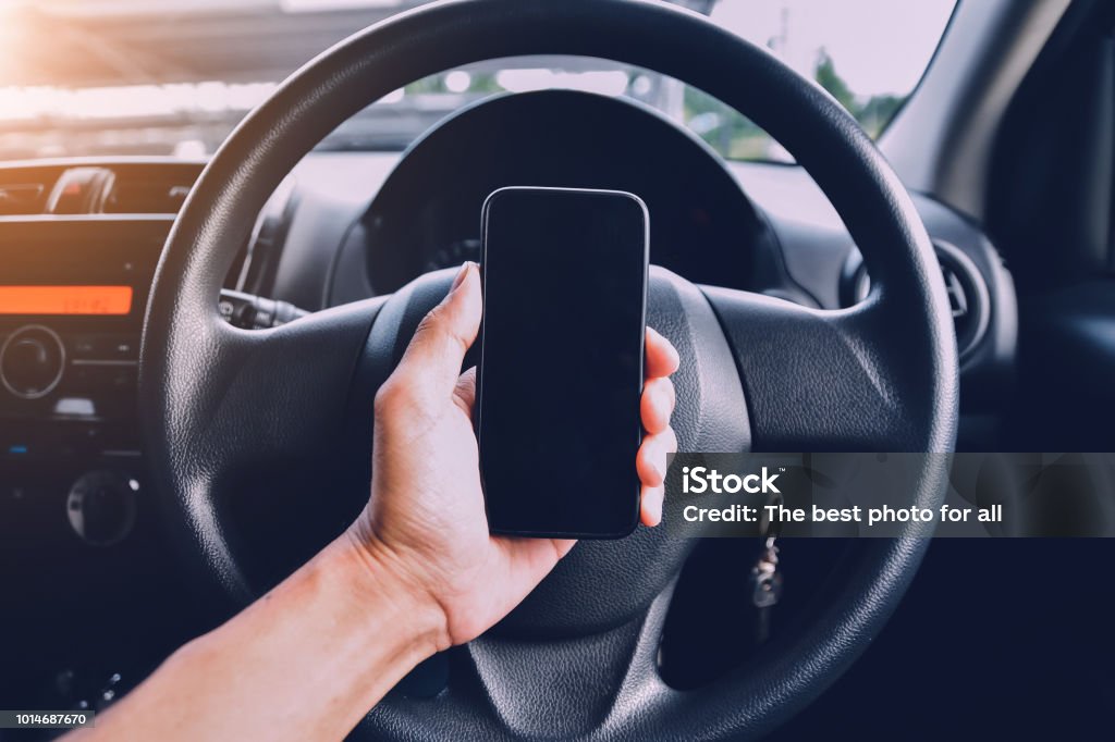 Hand holding smartphone in car parked on street.And using smartphone to shopping online by internet Smart Phone Stock Photo