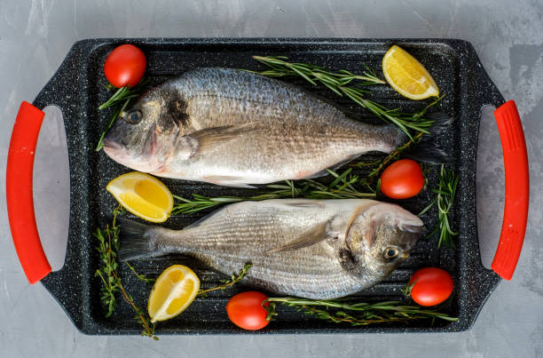 istock Fresh Raw Dorado with lemon, thyme, cherry and rosemary . 1014704424