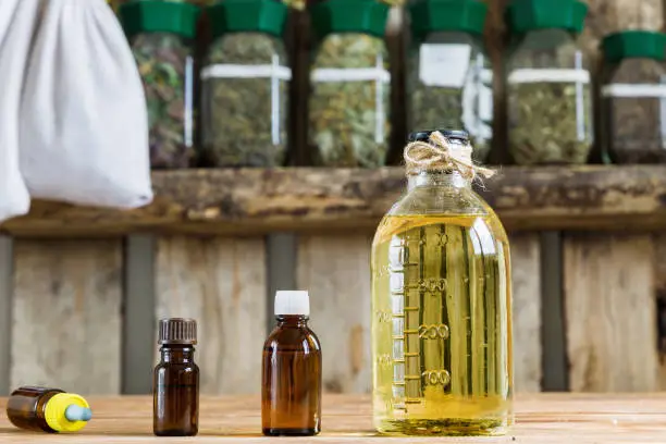 Essential oils and oil food, dry herbs. Against background of medicinal herbs in glass jars