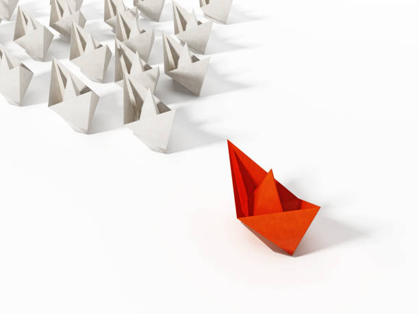 istock Red paper ship leading large group of white ships 1014712172