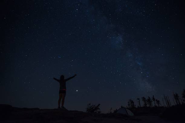 istock Young woman enjoying starry night on mountain trail 1014712346
