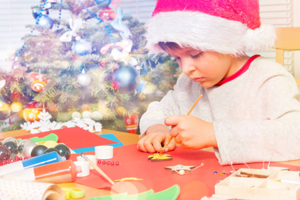 istock Boy in Santa costume decorating holiday ornaments 1014715564