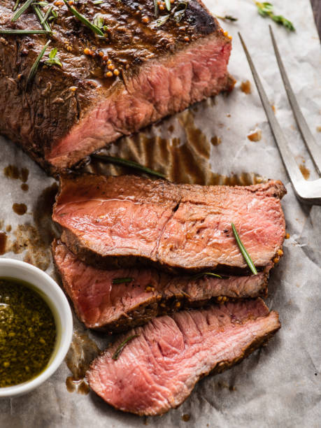istock Sliced Roast beef on white paper on wooden table with grilled vegetables. 1014725846