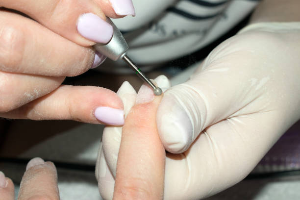 istock Process hardware (mechanical) manicure close-up. Nail treatment with electric nail drill. Selective focus on the bit and the nail of customer. Concept body care. 1014732930