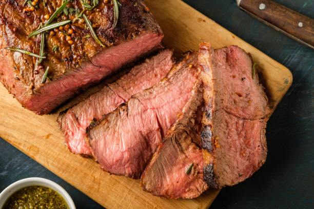 istock Sliced Roast beef on cutting board with grilled vegetables. Top view 1014733196
