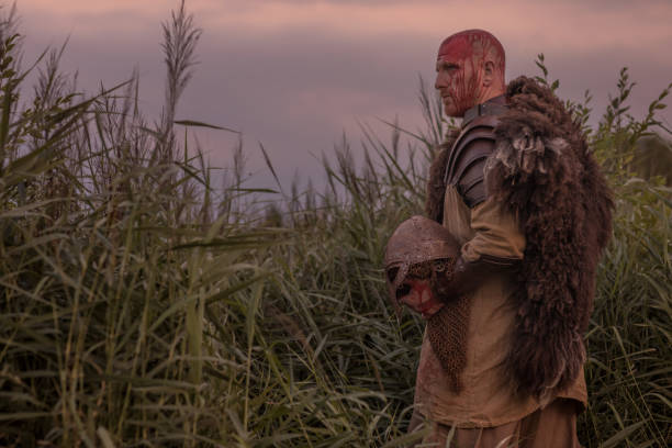 istock Sword wielding redhead bloody viking warrior alone in a grassy springtime field 1014741478