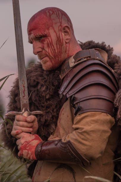 istock Sword wielding redhead bloody viking warrior alone in a grassy springtime field 1014742992