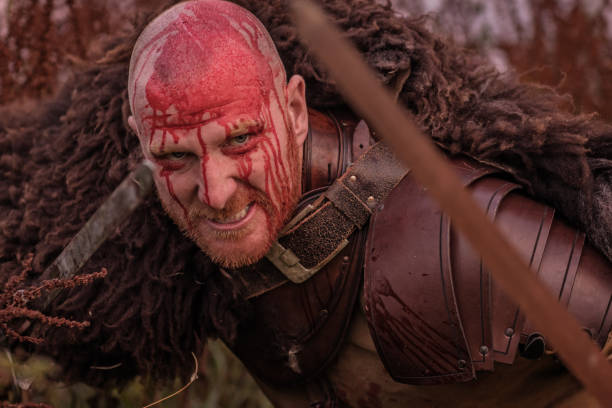 istock Sword wielding redhead bloody viking warrior alone in a grassy springtime field 1014745056