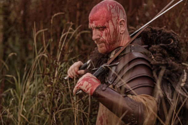 istock Sword wielding redhead bloody viking warrior alone in a grassy springtime field 1014745116