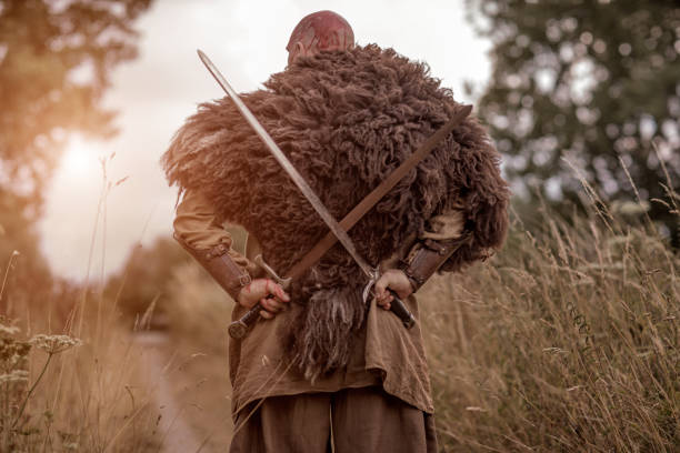 istock Sword wielding redhead bloody viking warrior alone in a grassy springtime field 1014745174