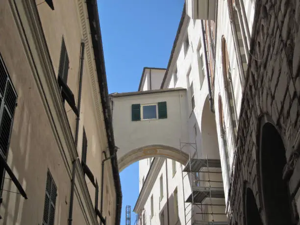A streetview in a small street in Genova with a bridge corridor