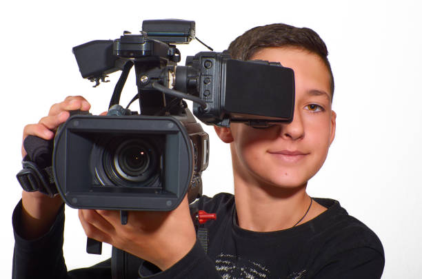 istock Teenage boy practicing filming with a professional video camera. 1014751808