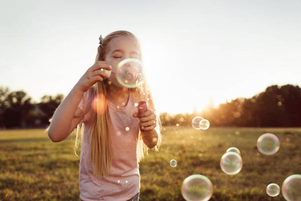 fille à faire des bulles de savon - bubble child bubble wand blowing photos et images de collection