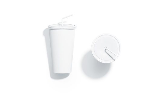 Blank white disposable cup with straw mockup top view, isolated, 3d rendering. Empty paper soda drinking mug mock up with lid and tube lies and stands. Clear soft drink cola take away plastic package