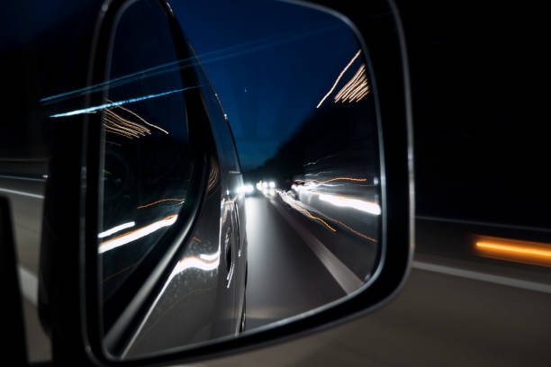 istock Traffic on highway at night - looking through rear view mirror 1014763034