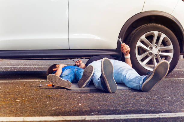 Father and son working under broken car together Father and son working under broken car together with their legs sticking out outside mechanic working under car stock pictures, royalty-free photos & images