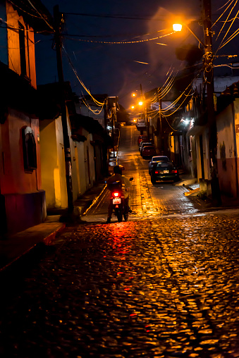 Street at night and motorcyclist riding on cobblestoned street in the old Spanish colonial centre, San Cristobal de las Casas, Chiapas, Mexico