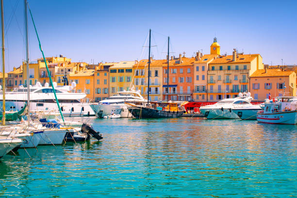 Saint Tropez, South of France. Luxury yachts in marina. Waterfront and harbor view of St Tropez with luxury boats and yachts. Colorful image with buildings in the background. france village blue sky stock pictures, royalty-free photos & images