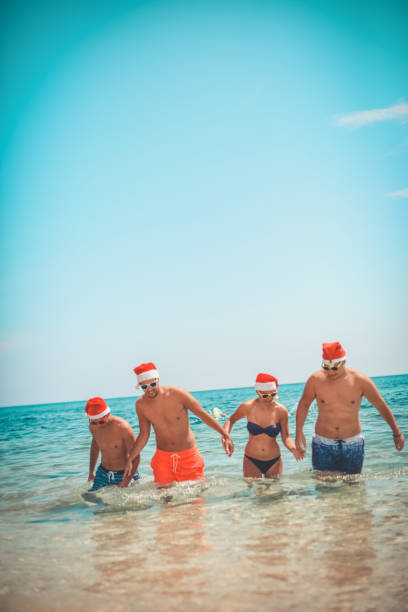 istock Friends on the beach with Santa Claus caps 1014766722