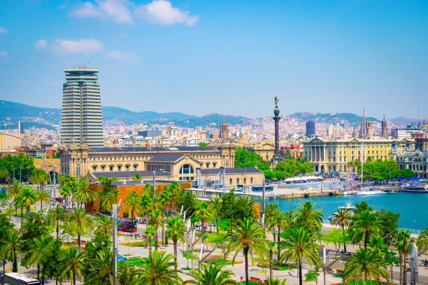 Landscape with cruise port and harbor of Barcelona in Spain. Colorful travel image with palm trees, popular buildings, water with boats and blue sky.
