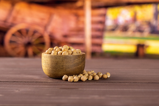 Lot of whole raw chickpeas kabuli variety with wooden bowl with cart in background