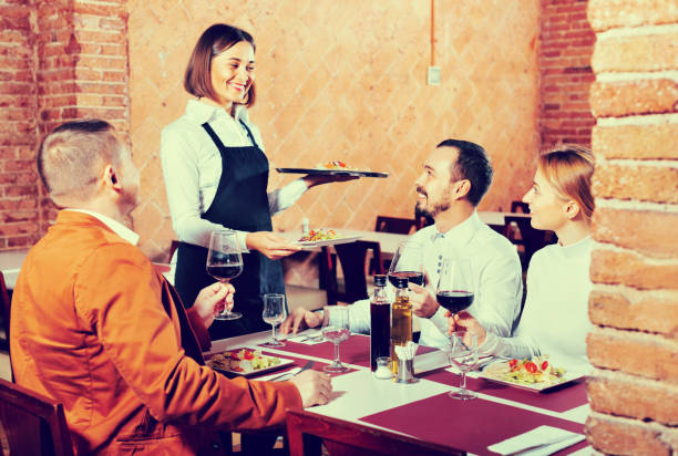 istock Female waiter bringing order to visitors 1014773700