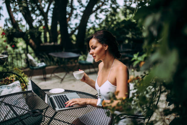 istock Drinking coffee and working on laptop in outdoors cafe. Freelance work concept. 1014773732