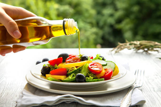 mano vierte el aceite de oliva en un plato con ensalada fresca de verano en el modo natural de fondo. - salad dressing condiment cooking oil glass fotografías e imágenes de stock