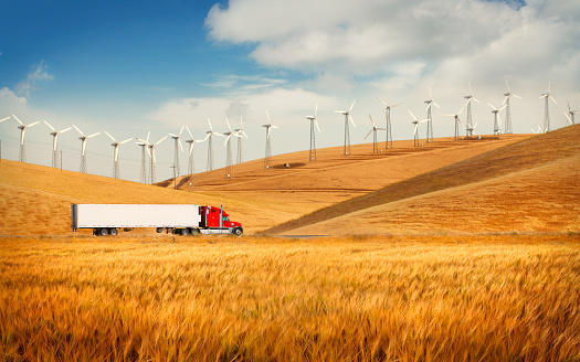 Truck going in the countryside with wind farm on the hills