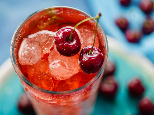 CLose-up of Iced organic cherry lemonade with fresh berries on the blue table, top view CLose-up of Iced organic cherry lemonade with fresh berries on the blue table, top view. carbonated juice stock pictures, royalty-free photos & images