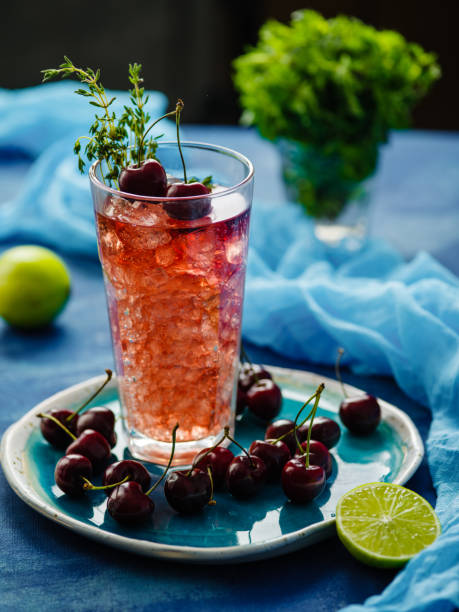 istock Iced fizzy organic cherry lemonade with fresh berries and thyme on the blue table. 1014785412