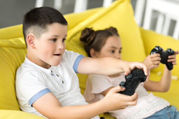 istock siblings playing video game on sofa at home 1014790980
